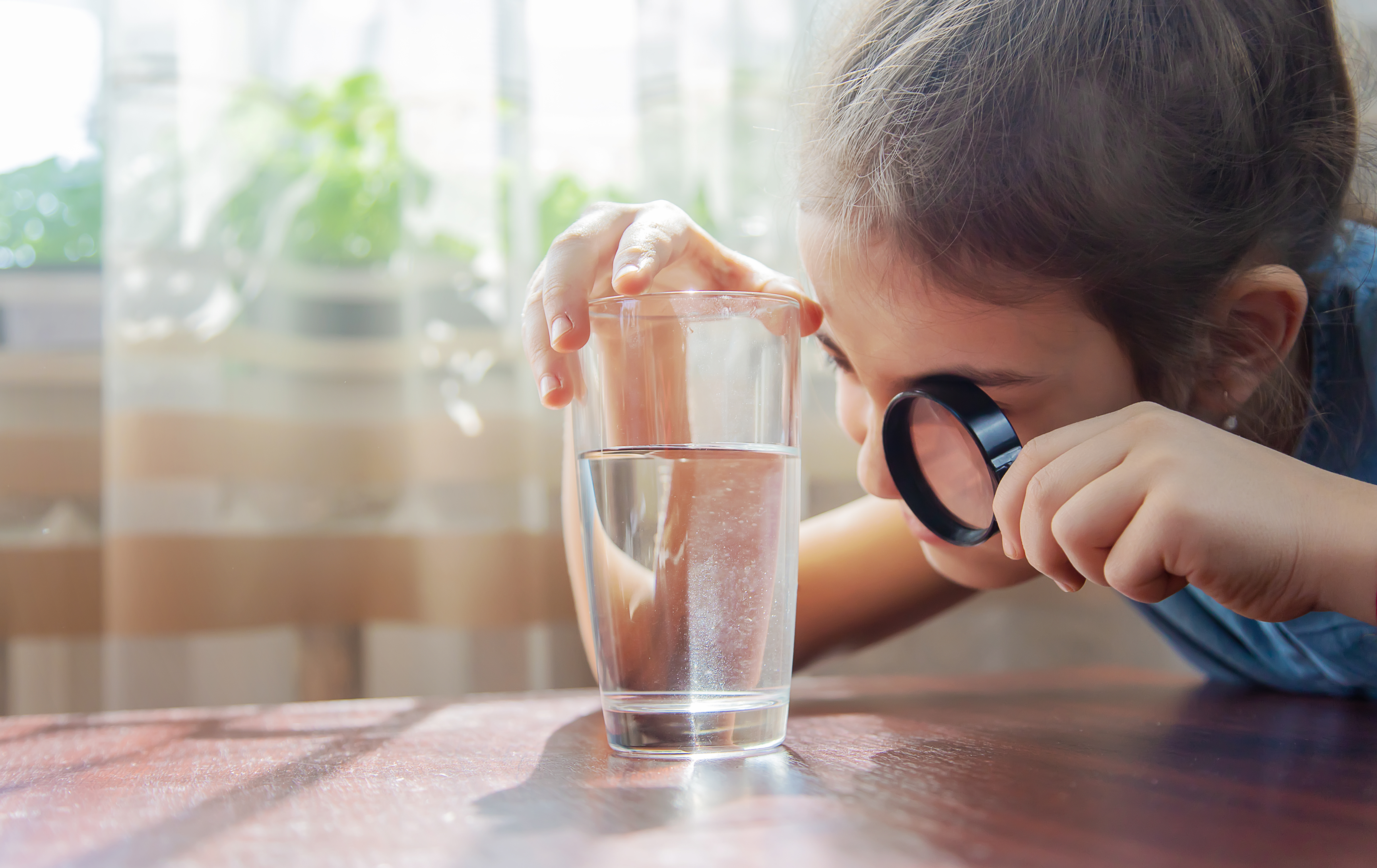A child looking into a glass of contaminated water
